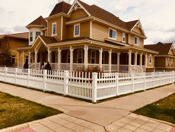 big-mocha-house-with-porch-and-white-security-fence-in-denver-co